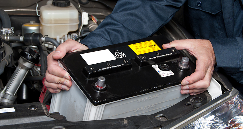 mechainic fitting new car battery, chosen from a range of car batteries