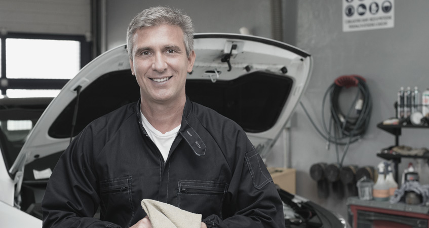 mechaninc smiling while cleaning hands on towel after performing car MOT testing